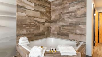 Un baño moderno con una bañera independiente, baldosas de mármol y toallas y artículos de aseo ordenados.