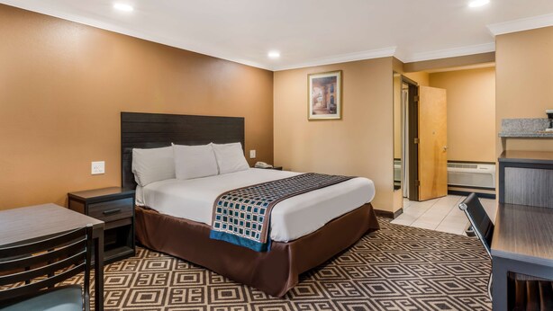 A hotel room with a large bed, a desk, a chair, and a small table. - Americas Best Value Inn Ukiah (Ukiah)