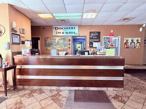 A reception desk with a sign for Discovery Inn & Suites, a pet policy notice, and a smoking no-smoking sign. - Discovery Inn Lafayette Airport I-10 (Lafayette)