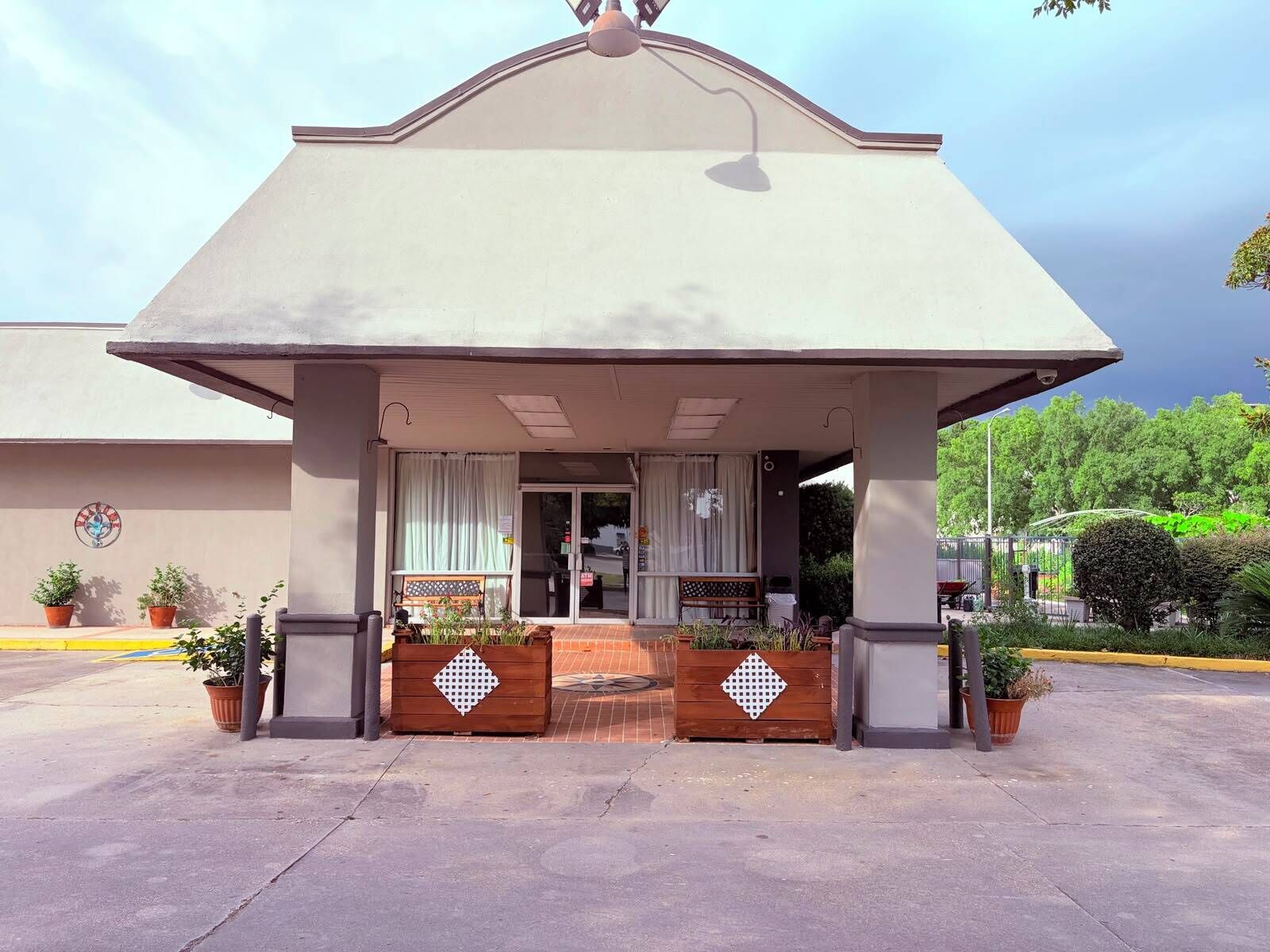Um edifício com entrada coberta, plantas em vasos e um banco.