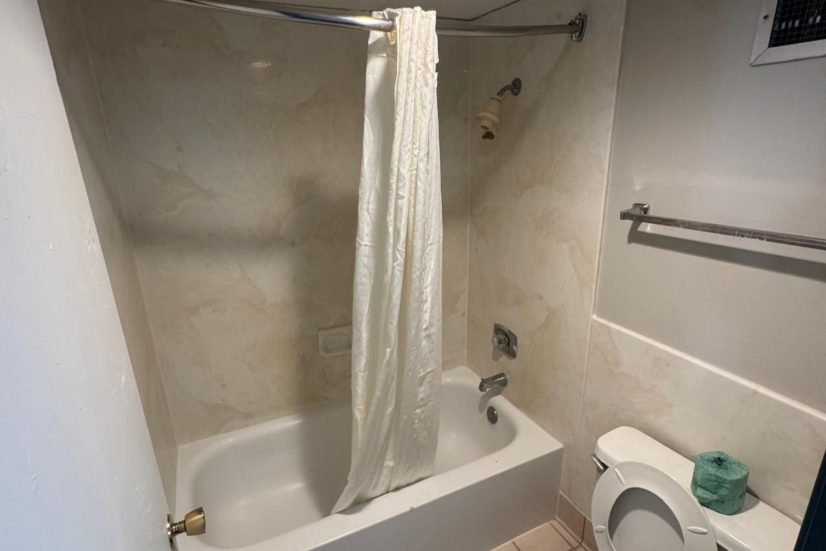 A bathroom with a bathtub, toilet, and shower curtain.