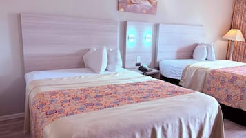 Quarto de hotel com duas camas, cabeceira, mesa de cabeceira com telefone e luminária.