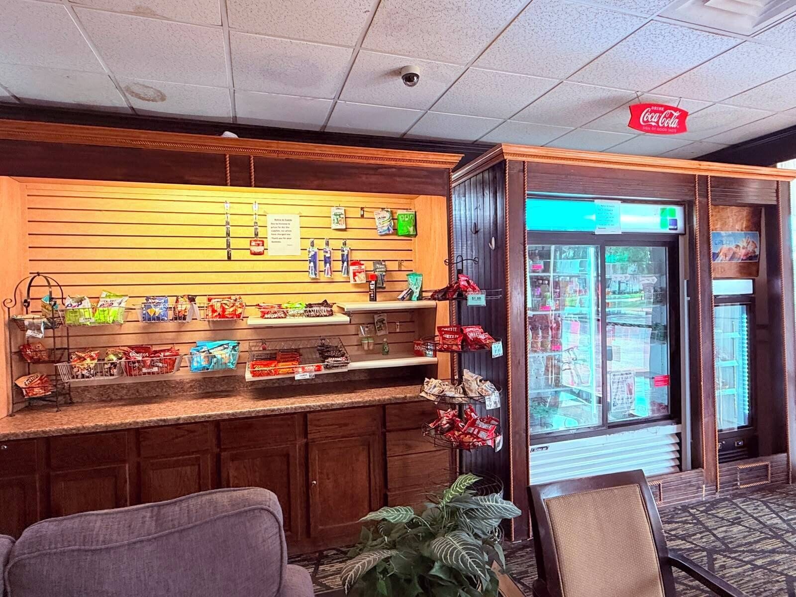 Um hall de hotel com um bar de lanches, área de estar e um letreiro da Coca-Cola.