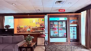 Un vestíbulo de hotel con zona de estar, bar de aperitivos y nevera para bebidas.