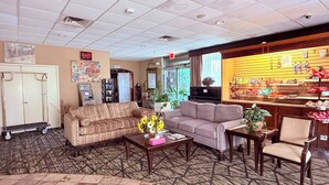 A lobby with sofas, a coffee table, a reception desk, and a snack bar. - Discovery Inn Lafayette Airport I-10 (Lafayette)