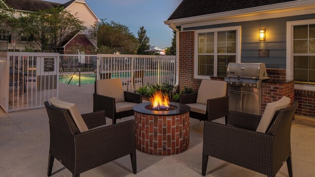 A patio with wicker chairs, a brick fire pit, and a grill area.