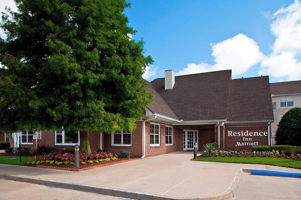 A brick building with a sign reading "Residence Inn Marriott" and a large tree in front.