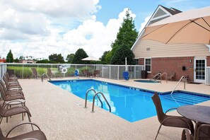 A swimming pool with lounge chairs and a covered seating area.