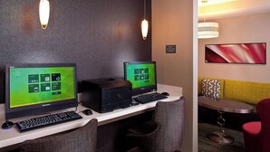 A hotel workspace with two Lenovo monitors, a printer, and a keyboard on a desk.