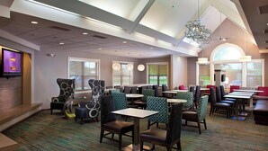 A modern restaurant with high ceilings, patterned carpet, and a variety of seating options including booths and tables.