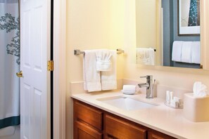 A bathroom with a white sink, a mirror, and a towel rack with multiple towels.