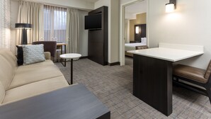 Habitació d'hotel amb un sofà, una taula petita, un televisor, un escriptori i una cadira.