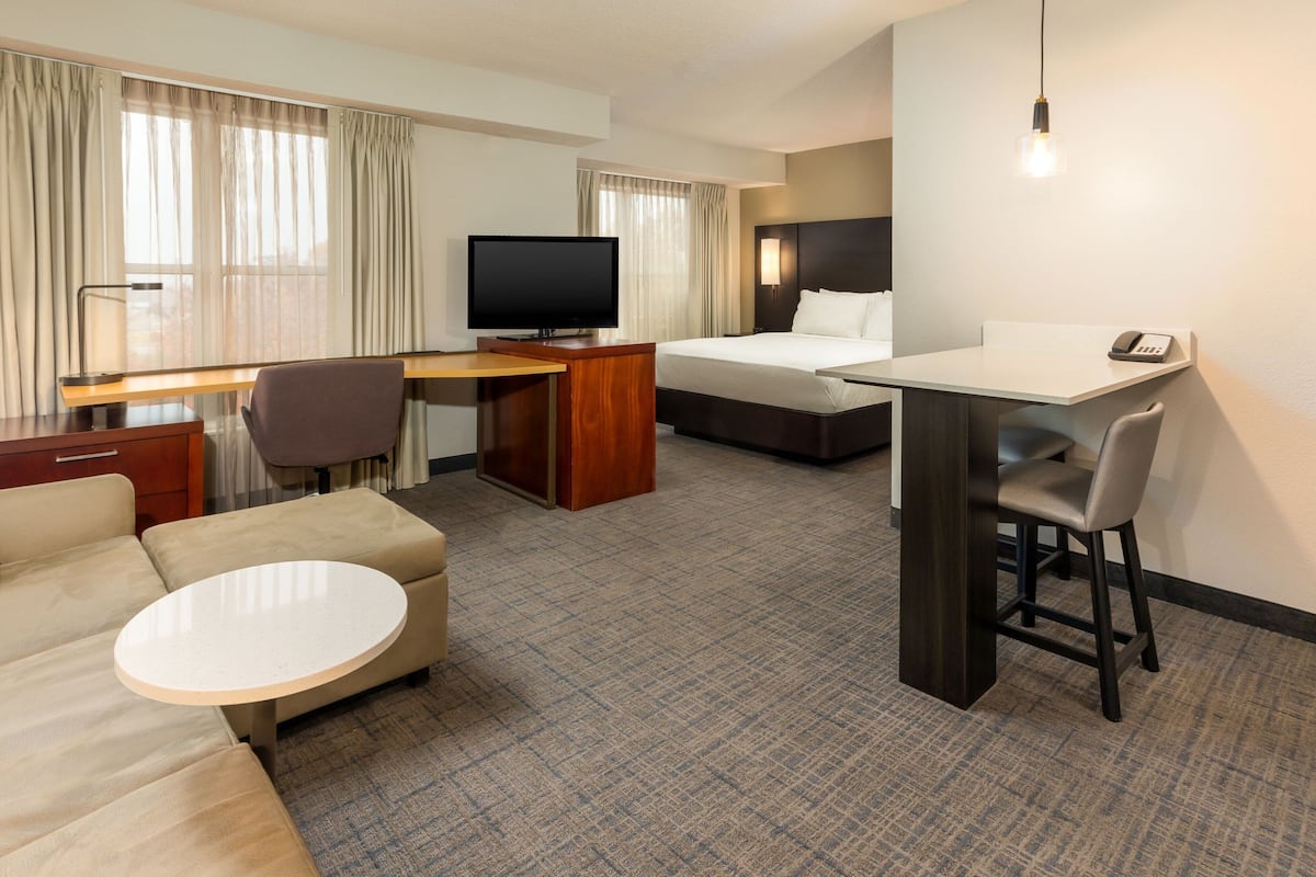 A hotel room with a bed, a desk, a television, a sofa, and a small table.