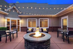 An outdoor patio with a stone fire pit, seating, and string lights. - Residence Inn by Marriott Vacaville (Vacaville)