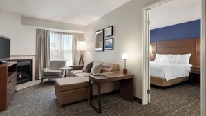 A hotel room with a bed, a sofa, a desk, a TV, and a fireplace. - Residence Inn by Marriott Vacaville (Vacaville)