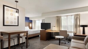 A hotel room with a bed, a desk with a computer, a TV, a sofa, and a small table with chairs. - Residence Inn by Marriott Vacaville (Vacaville)