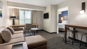 A hotel room with a sofa, a desk, a chair, a bed, and a TV. - Residence Inn by Marriott Vacaville (Vacaville)