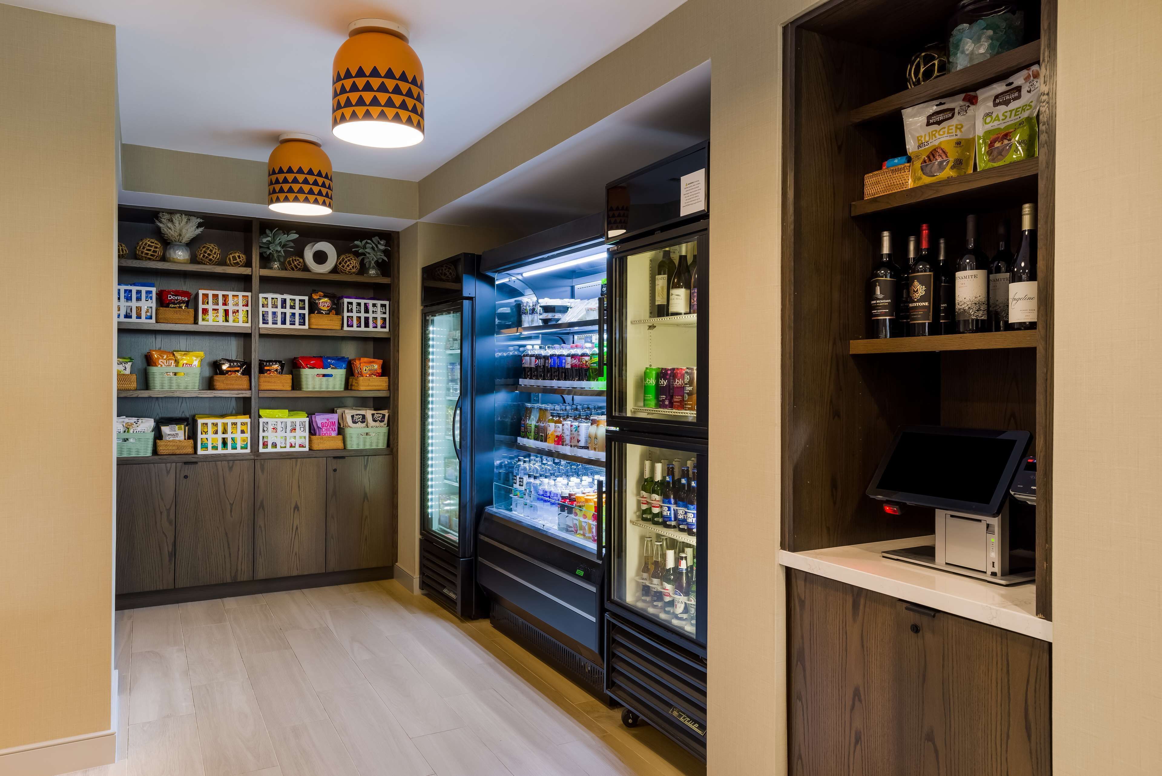 Un hall d’hôtel équipé d’un espace de libre-service pour les boissons, de distributeurs de collations et d’un réfrigérateur à vin.