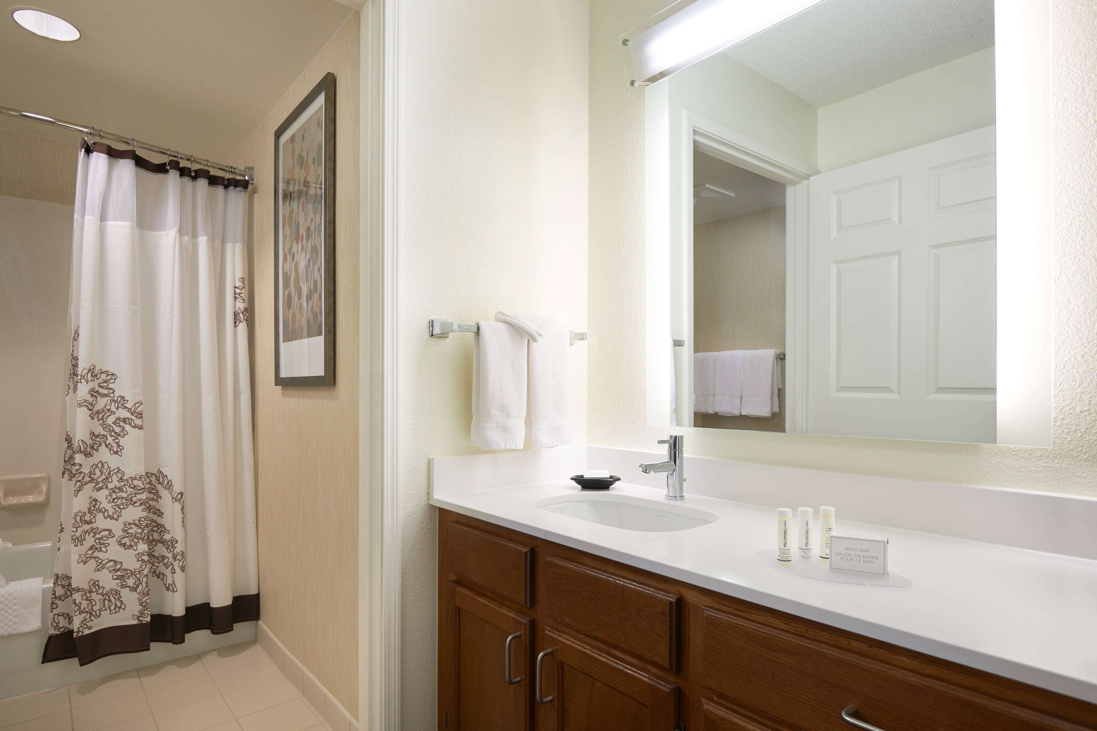 A bathroom with a white sink, a large mirror, and wooden cabinets.