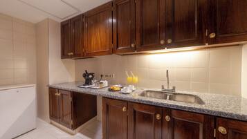Una cocina con armarios de madera, encimera de granito, un lavabo y una cafetera.