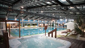 Piscina interna com hidromassagem, espreguiçadeiras e área de estar coberta.