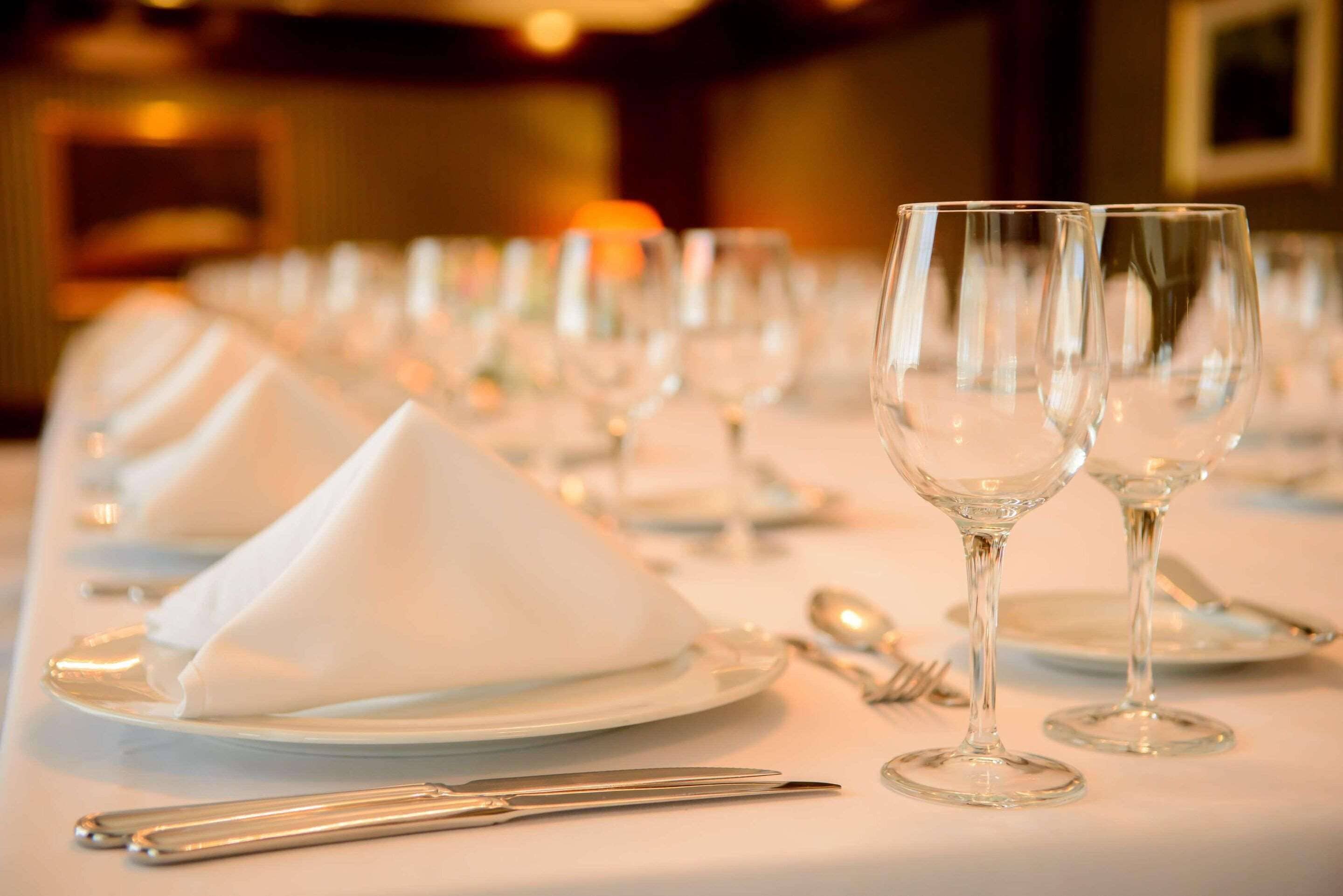 A table set for a formal dining experience with white napkins, clear glassware, and silverware.
