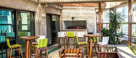 An outdoor patio with wooden furniture, a brick wall, and a hanging plant.