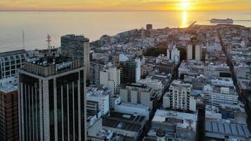 A cityscape with a prominent Radisson hotel, dense urban buildings, and a sunset over the sea.