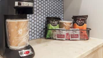 Máquina de café e um cesto com cápsulas de café Cafe Valet em uma bancada.