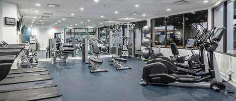 Une salle de sport équipée de tapis de course, de vélos elliptiques et de matériel de musculation.
