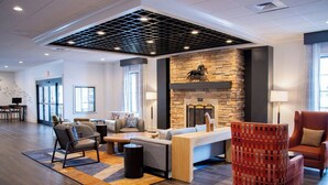 Een moderne lobby met een stenen openhaard, zithoek en een gestreept stoel.
