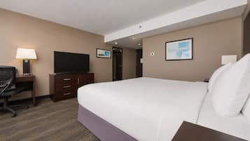 Une chambre d’hôtel comprenant un lit, un bureau, une télévision et une porte donnant sur une autre pièce.
