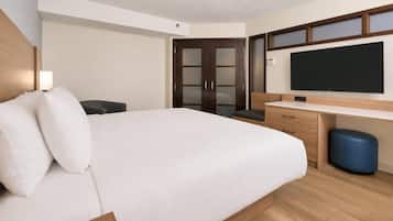 Habitación de hotel con cama, escritorio, silla, televisor y armario.