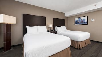 Habitación de hotel con dos camas, una mesita de noche, una lámpara y un cuadro en la pared.