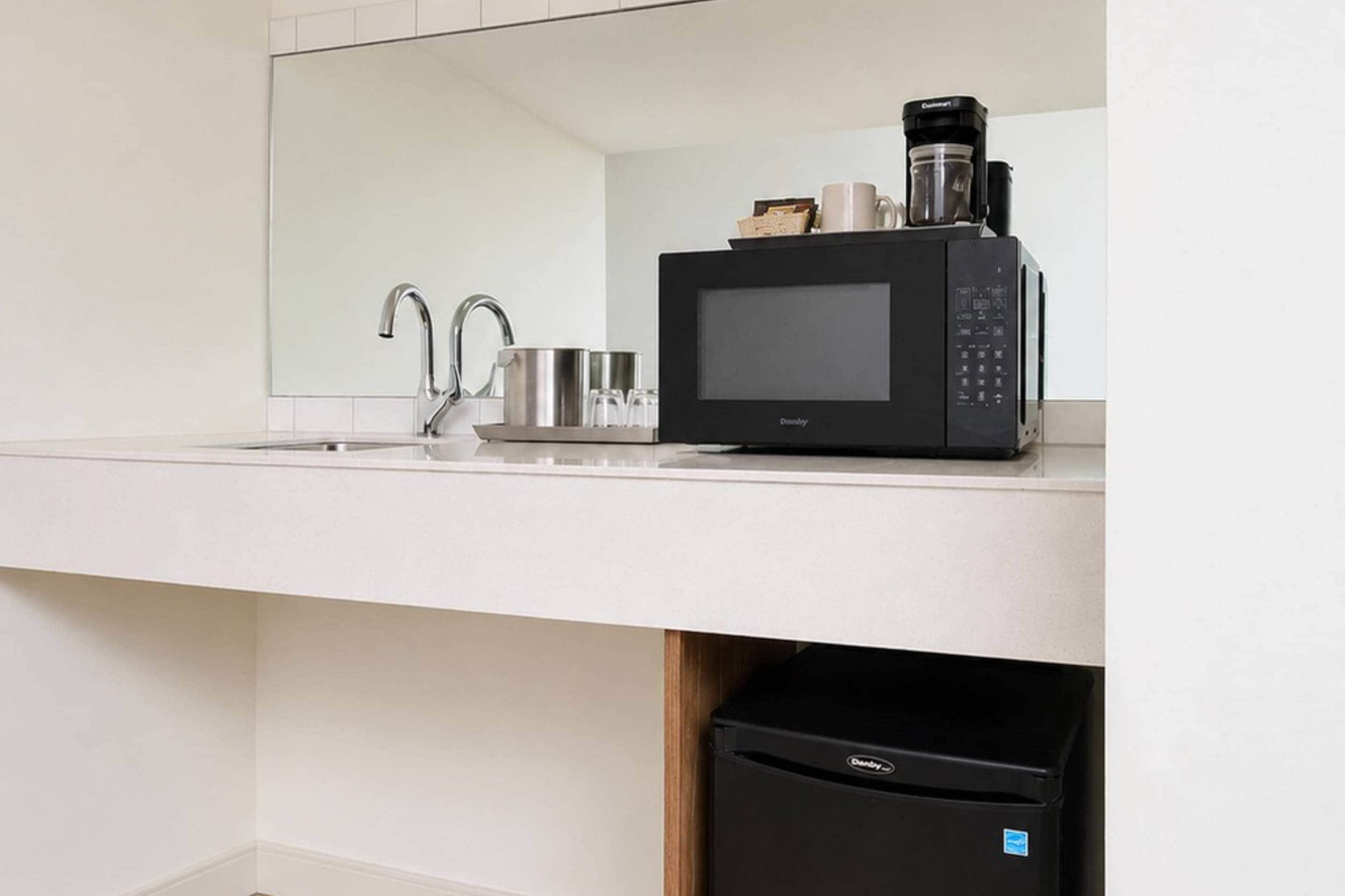 Une cuisine moderne équipée d’un four à micro-ondes encastré, d’une machine à café et d’un évier.