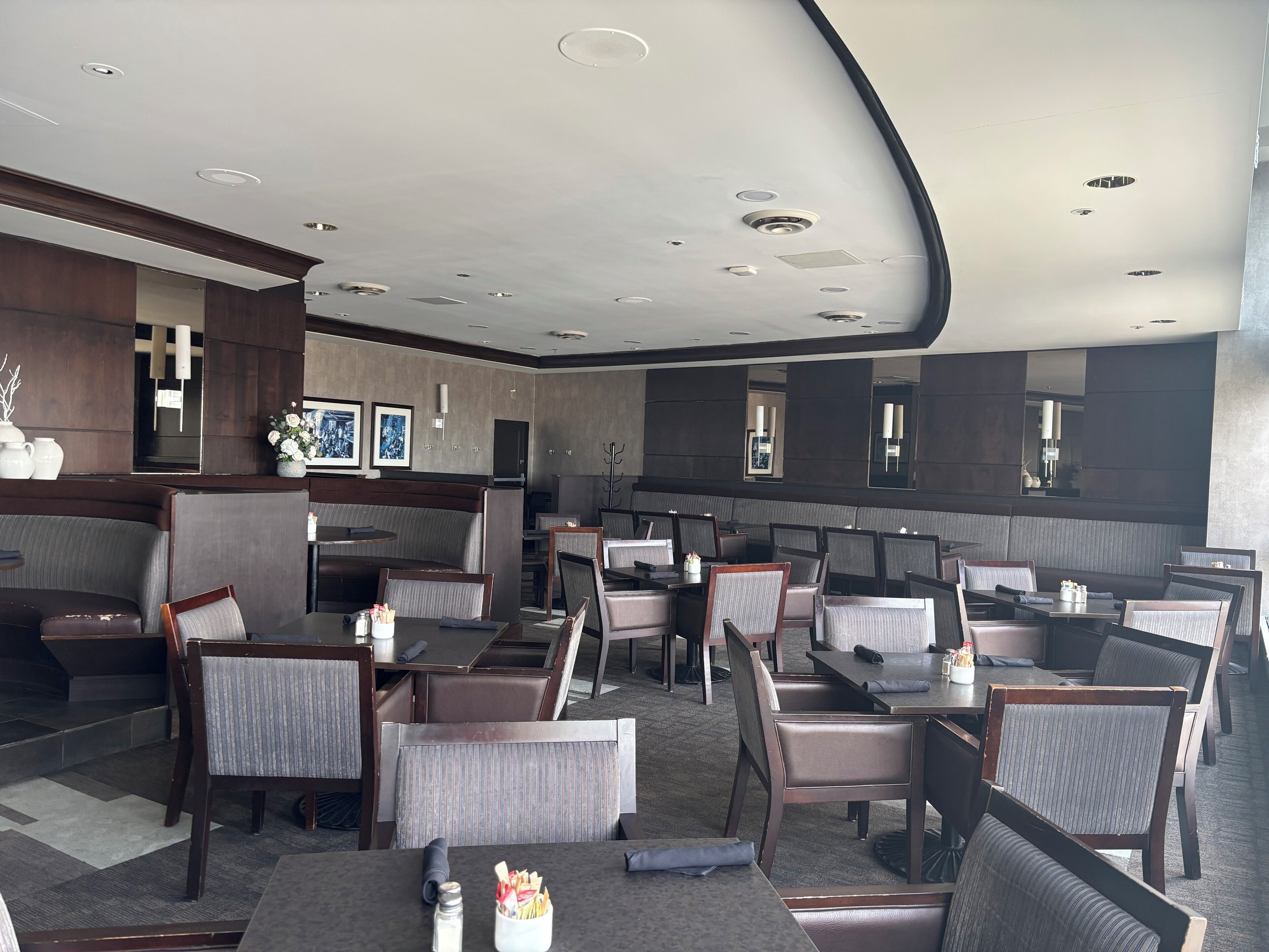 A modern restaurant with high-backed chairs, round tables, and a central bar area.