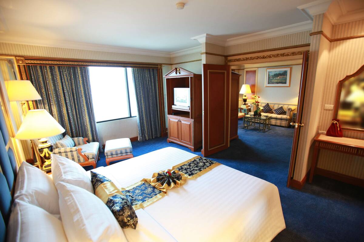 A hotel room with a large bed, a desk, a chair, and a television.