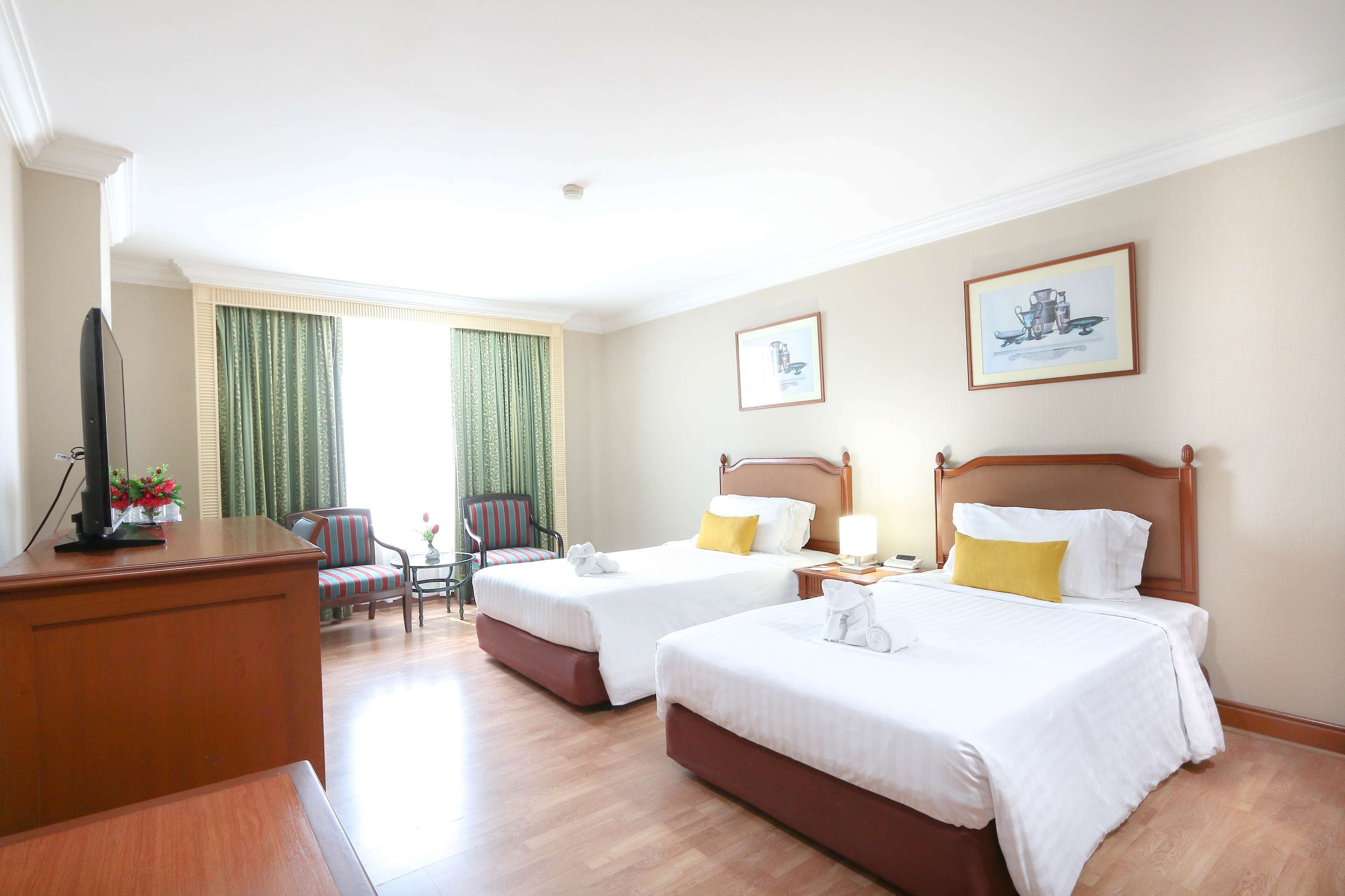 Habitación de hotel con dos camas, un escritorio, una silla y un televisor.
