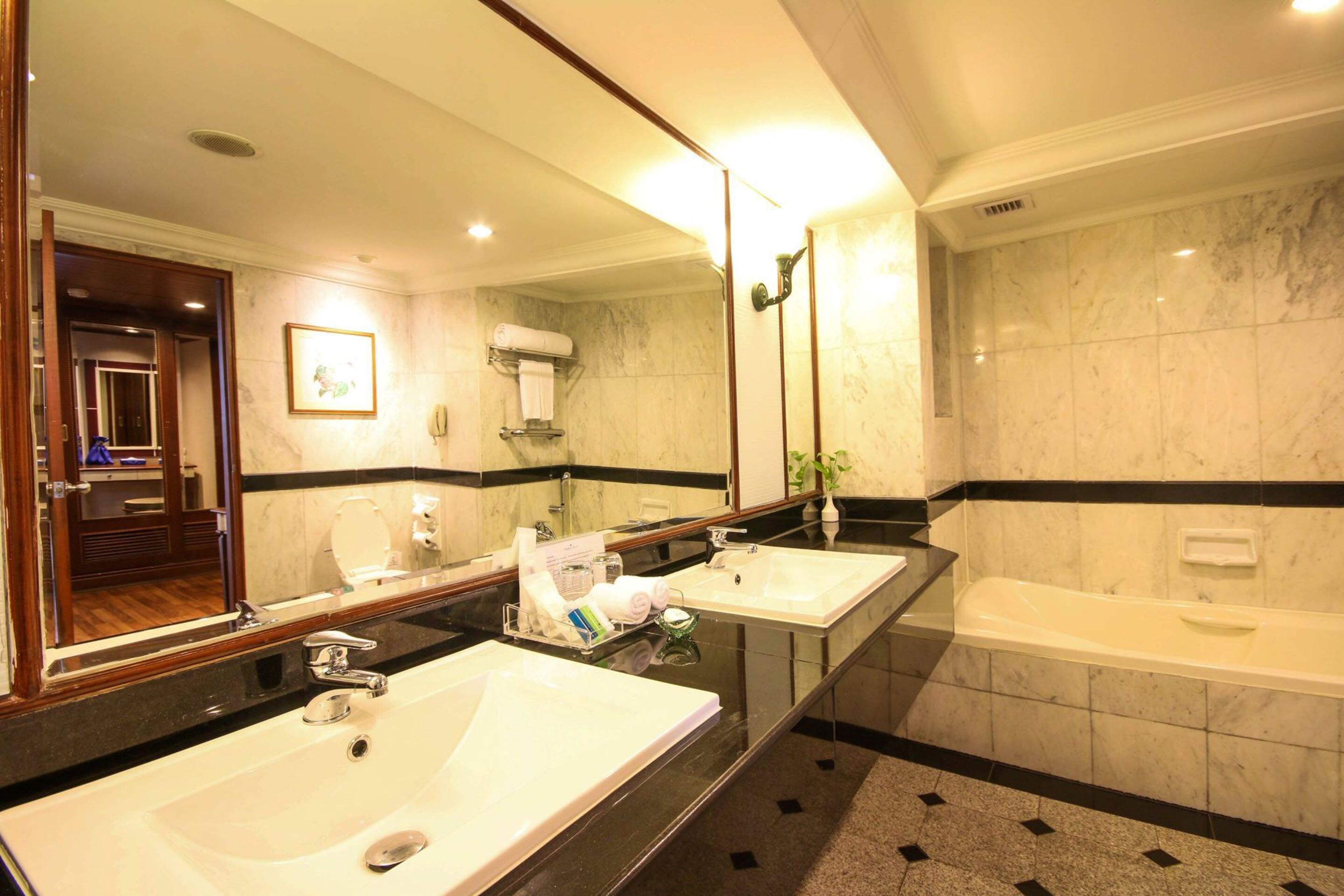Un baño de hotel con dos lavamanos, un espejo grande y una bañera.