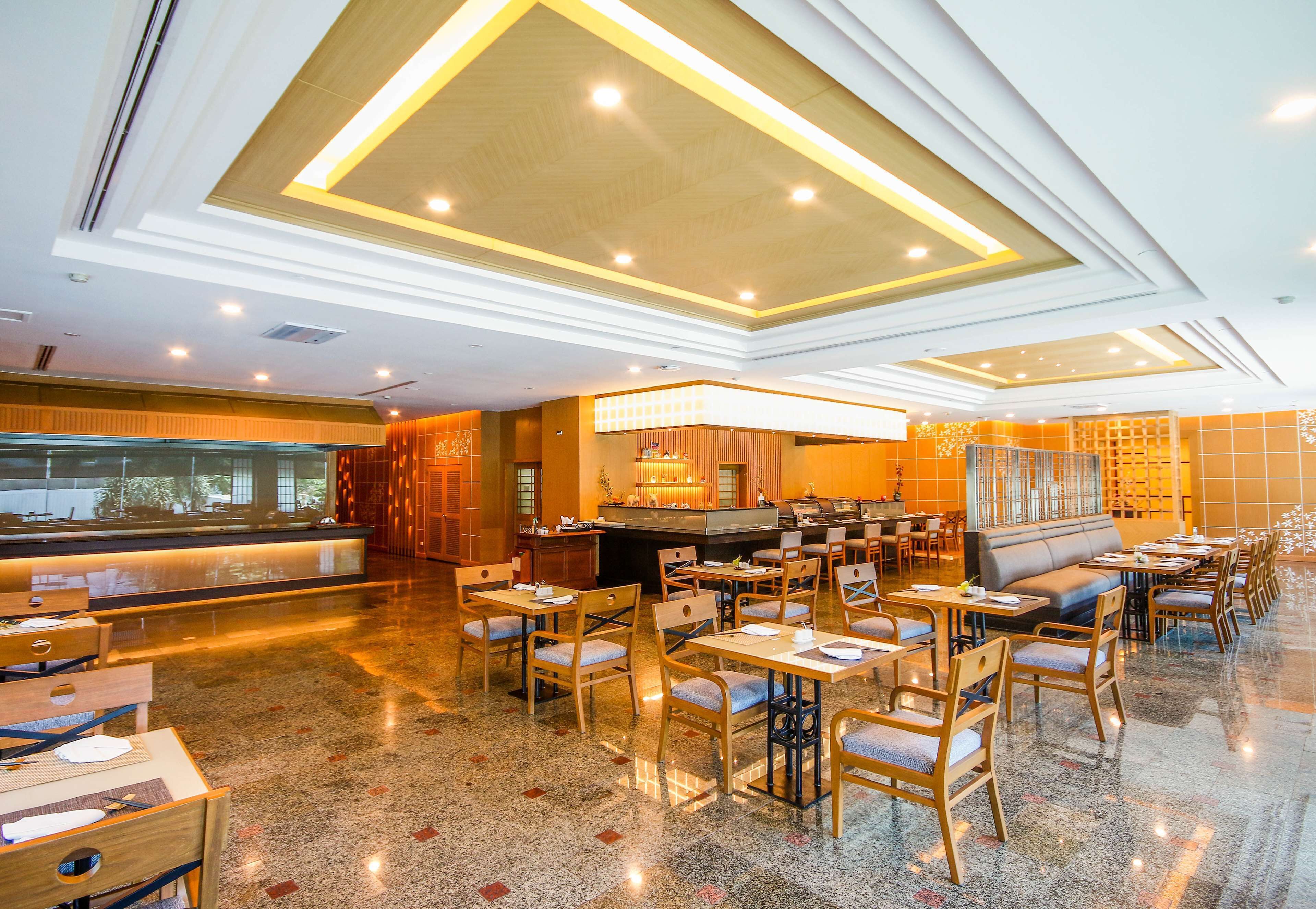 A spacious hotel lobby with a central bar area, multiple seating arrangements, and a polished floor.