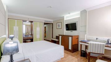 Une chambre d’hôtel comprenant un lit, un bureau, une télévision, une armoire et un miroir.
