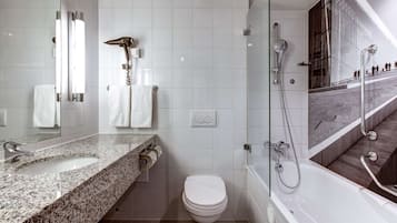 A modern bathroom with a granite countertop, a toilet, a shower with a glass enclosure, and a bathtub.