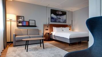Ein modernes Hotelzimmer mit Bett, Sofa und kleinem Tisch.
