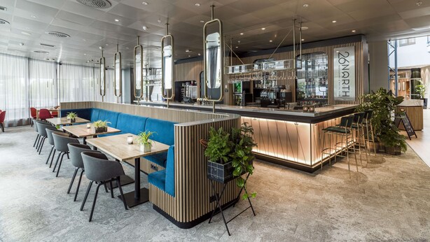 A modern restaurant with a central bar area, seating arrangements, and a visible kitchen in the background. - Radisson Blu Airport Hotel, Oslo Gardermoen (Ullensaker)