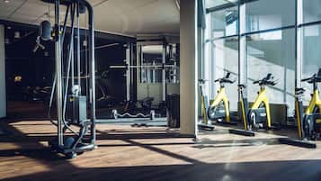A gym with exercise equipment, a weight rack, and a large window allowing natural light.