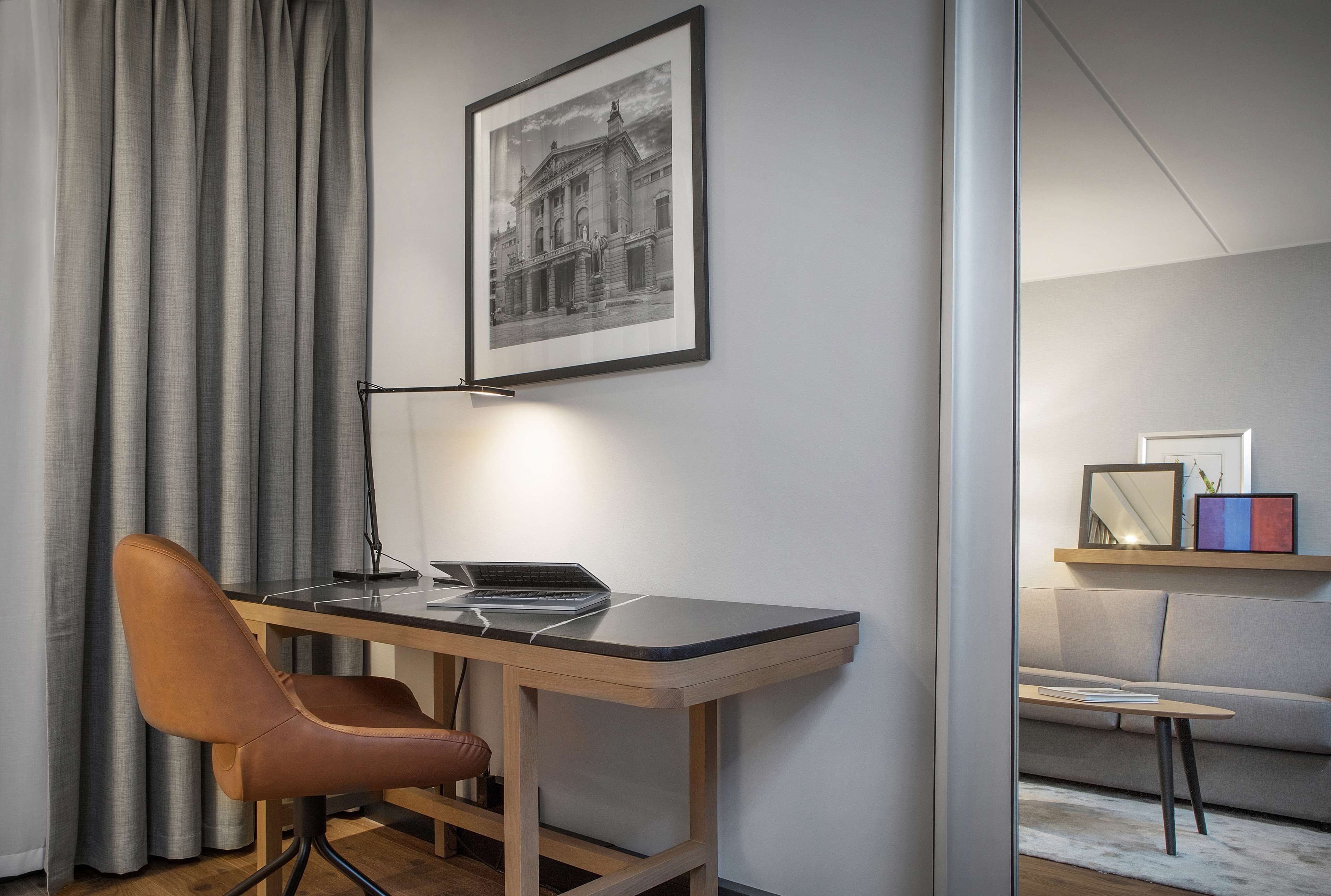 Une chambre moderne équipée d’un bureau, d’une chaise et d’un tableau encadré au mur.