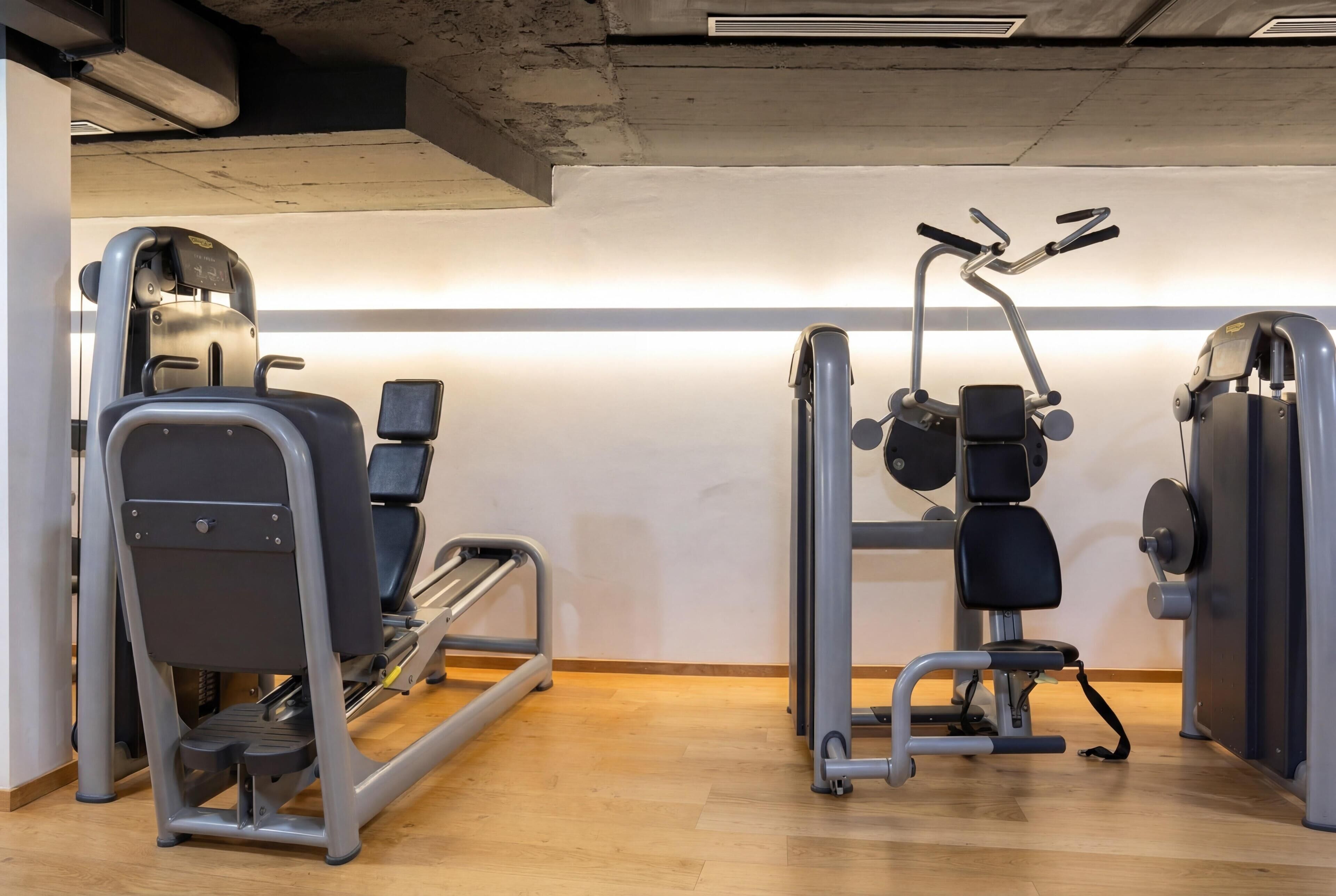 Un gimnasio con cintas de correr, escaladora y máquina de pesas.