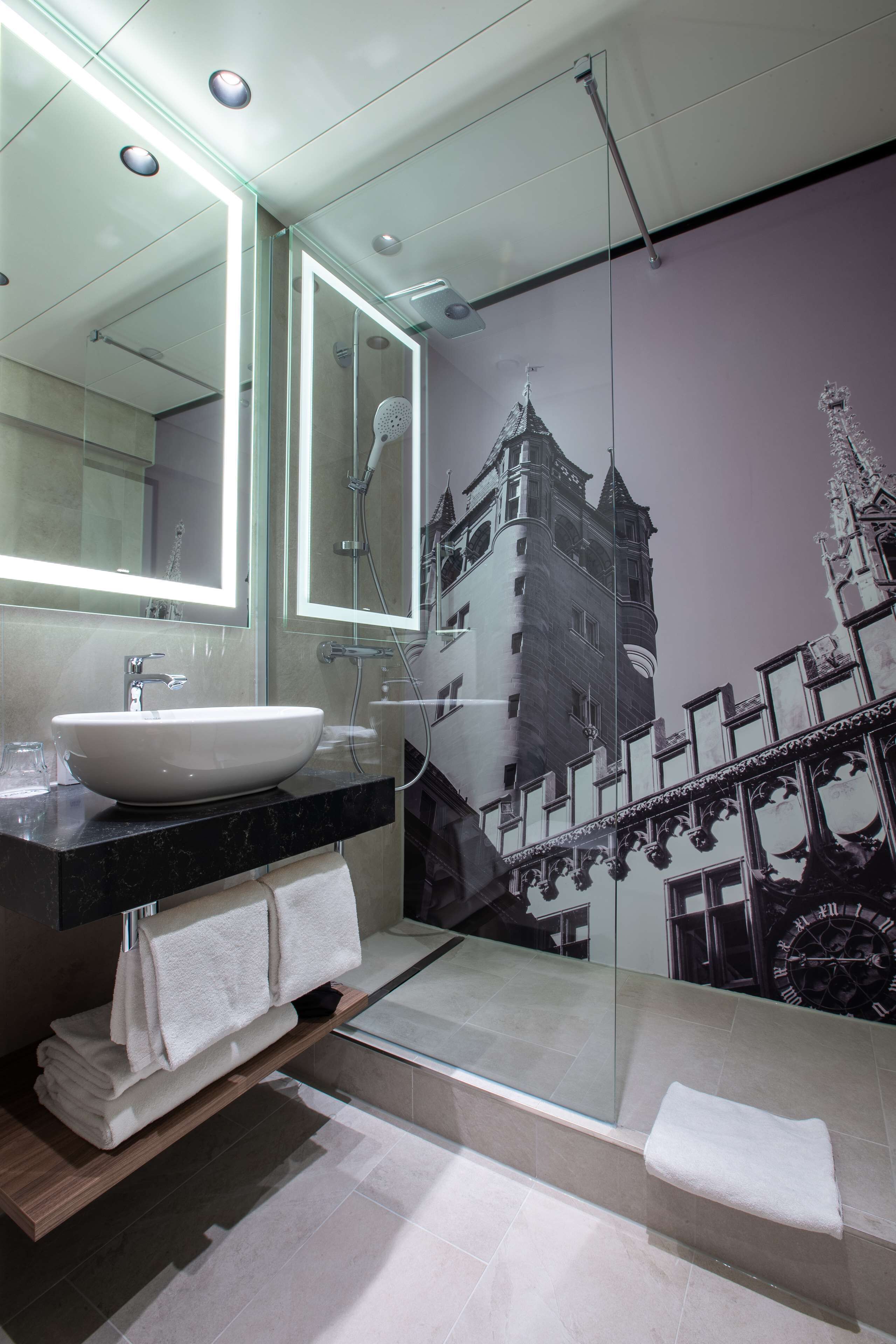 A modern bathroom with a large mirror, a sink, and a shower.