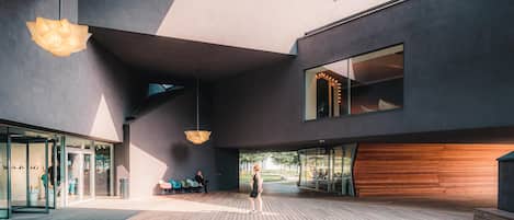 Un edificio moderno con amplios ventanales, una terraza de madera y lámparas colgantes.
