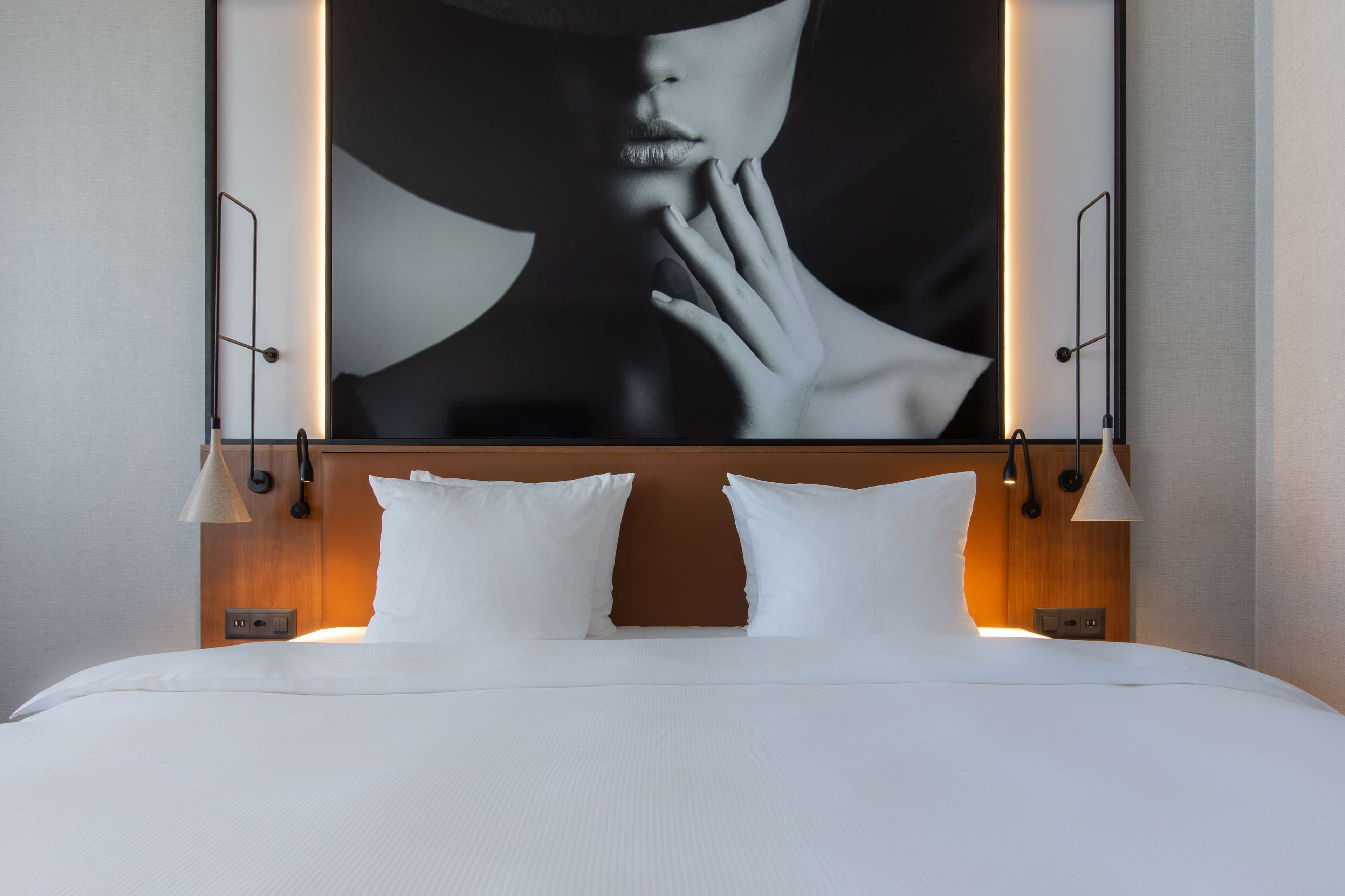 Una habitación de hotel con una cama grande, dos lámparas de noche y una obra de arte colgada en la pared.